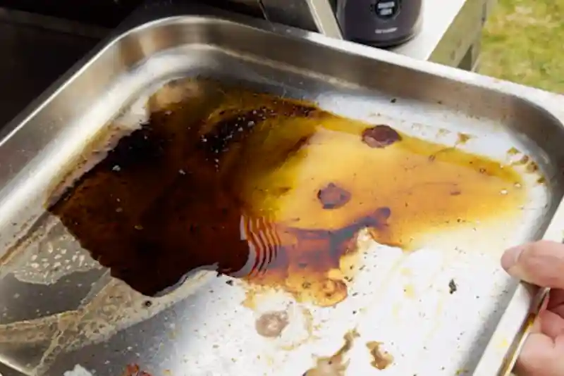 Fettauffangschale eines Oberhitzegrills mit Fett und Ablagerungen